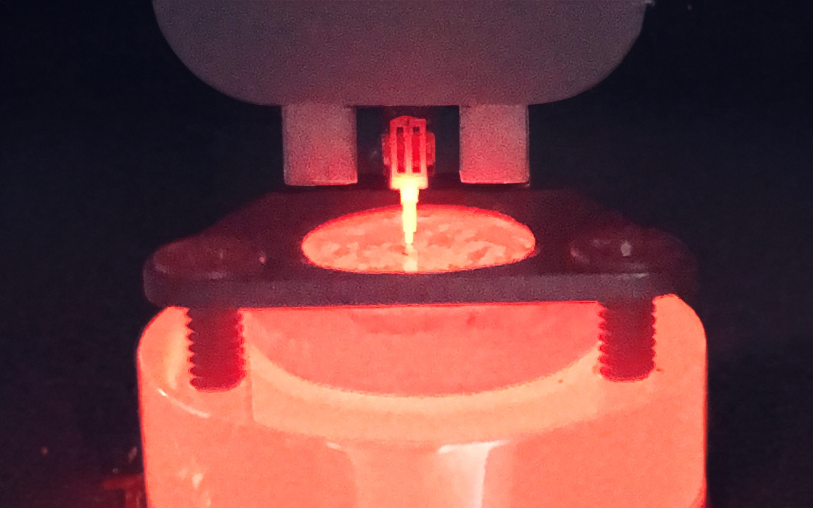 <p>Close-up view of nanoindentation test with a glowing indenter tip during high-temperature testing.</p>